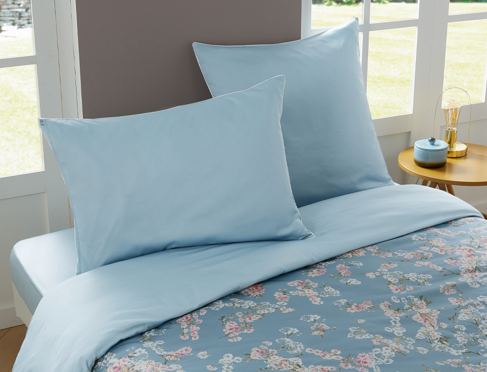 Linge de lit imprimé fleuri avec touches de blanc mat. Uni bleu ciel. Satin 100% coton, 118 fils/cm2. Florescence