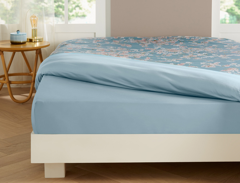 Linge de lit imprimé fleuri avec touches de blanc mat. Uni bleu ciel. Satin 100% coton, 118 fils/cm2. Florescence